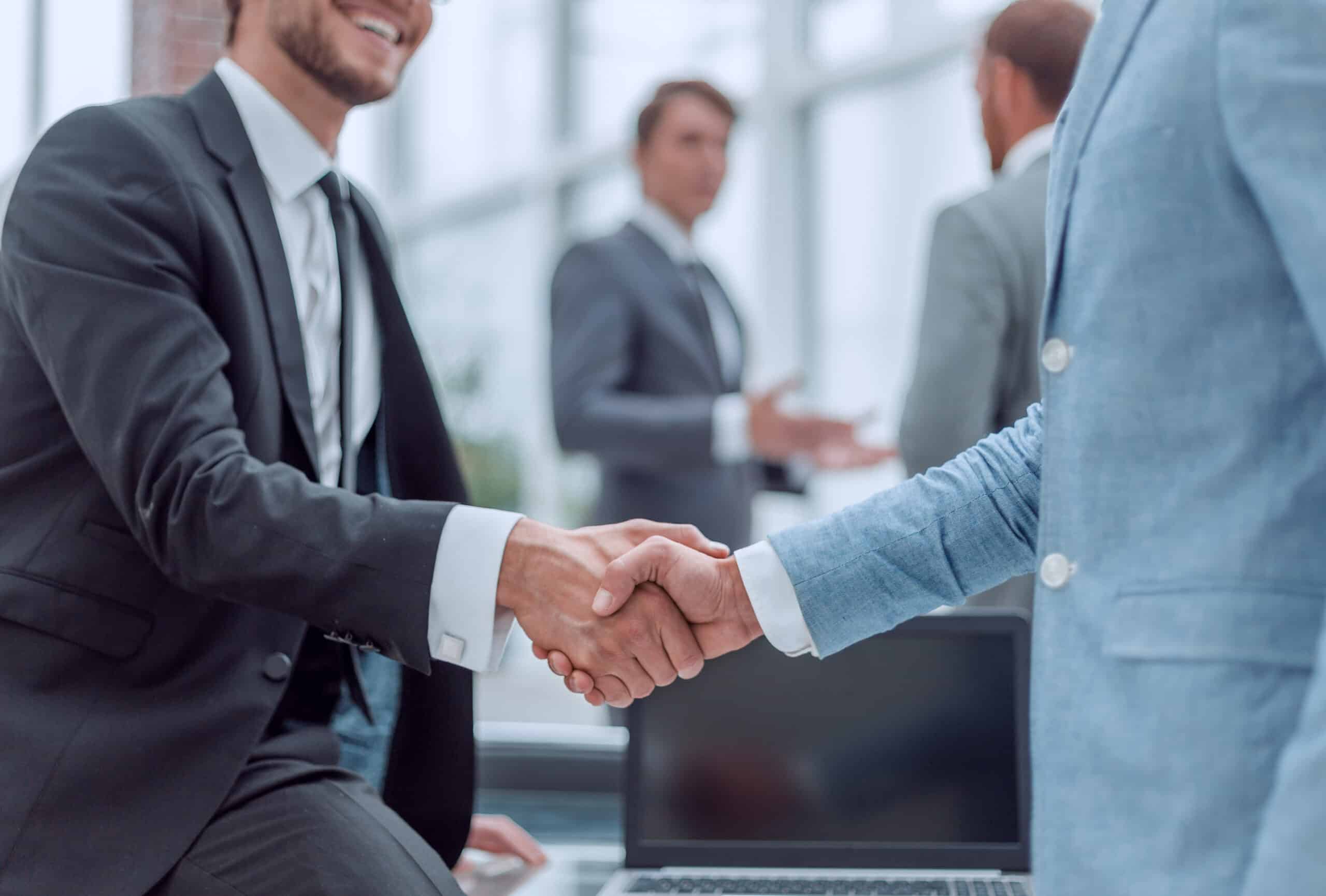 happy young businessman shaking hands with his business partner Partnering with Next Stage Payments for custom payment processing solutions for businesses